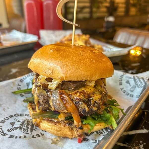 A Gourmet Burger Bistro burger with melted cheese, caramelized onions, and lettuce on a bun.