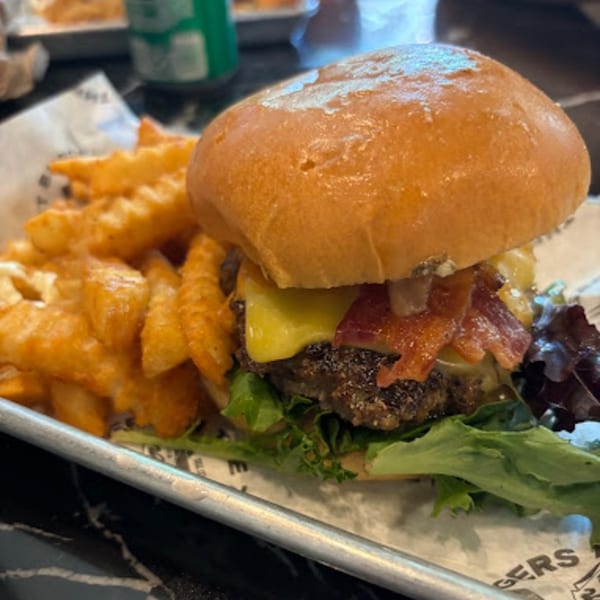 A Gourmet Burger Bistro cheeseburger with bacon and lettuce, served with waffle fries.